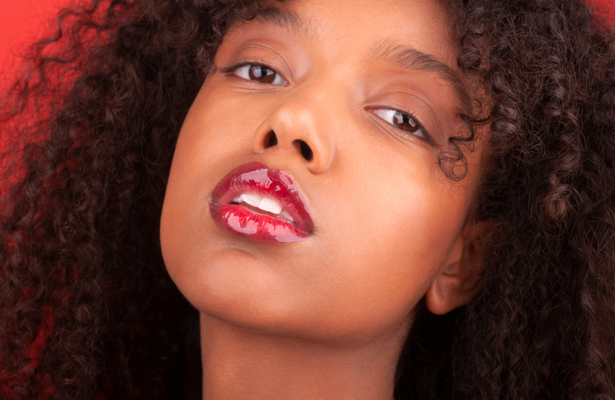 model`s face with vivid red lipstick and lip gloss applied